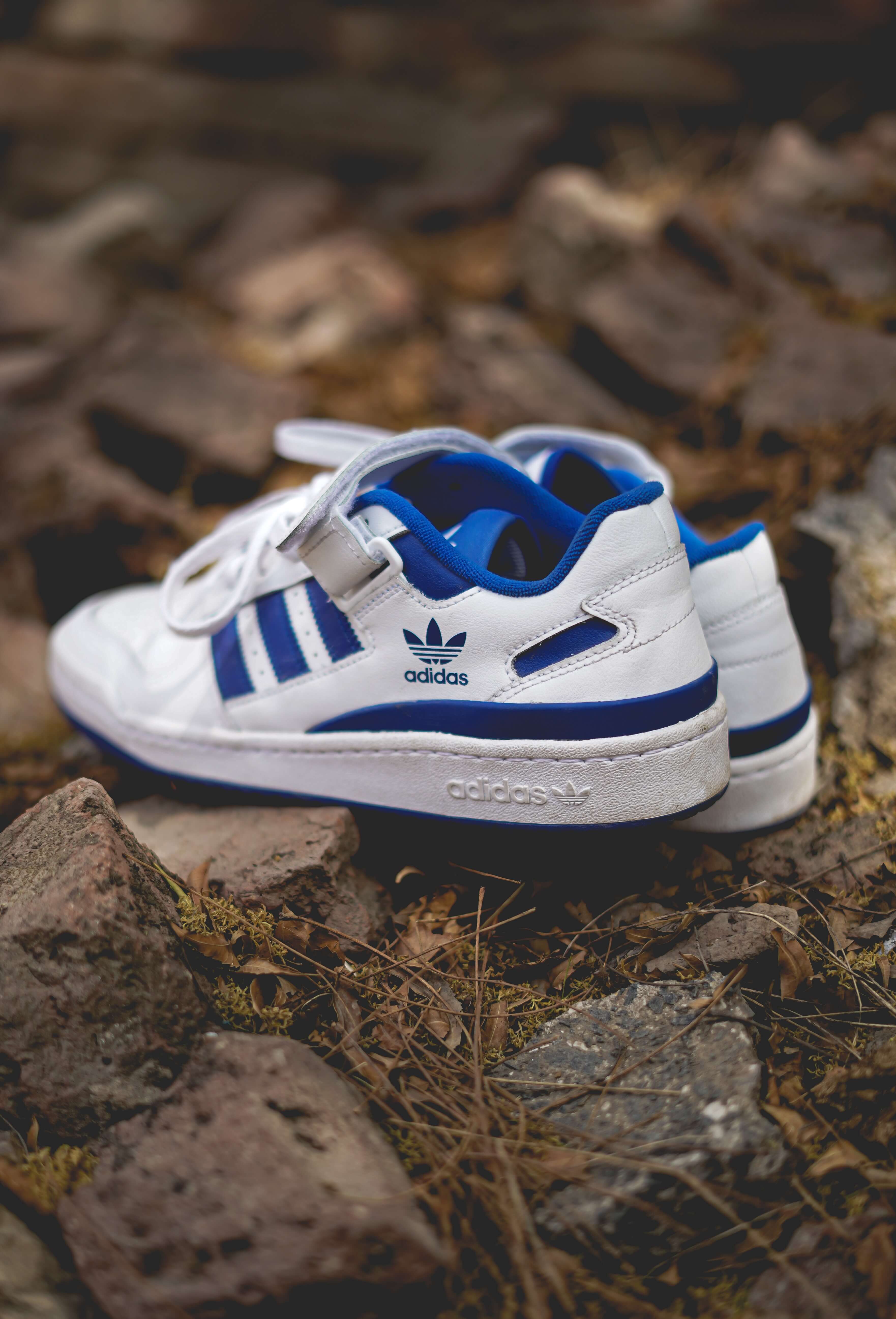 Blue and white ADIDAS trainers on the ground