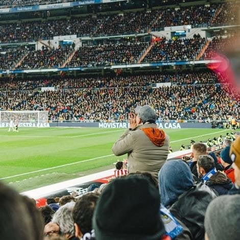 Man standing up in the crowd cheering at football